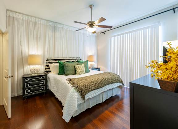 A bedroom with a bed, nightstand, and a ceiling fan.