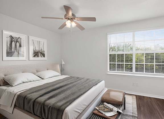 A bedroom with a bed, a ceiling fan, and two framed pictures on the wall.