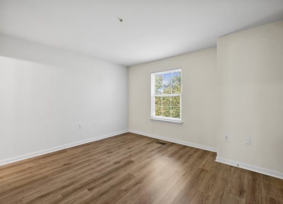 a room with white walls and a window and wooden floors