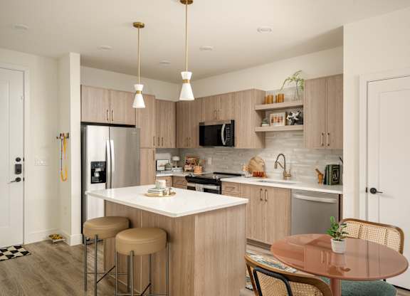 A kitchen with a refrigerator, microwave, and oven.
