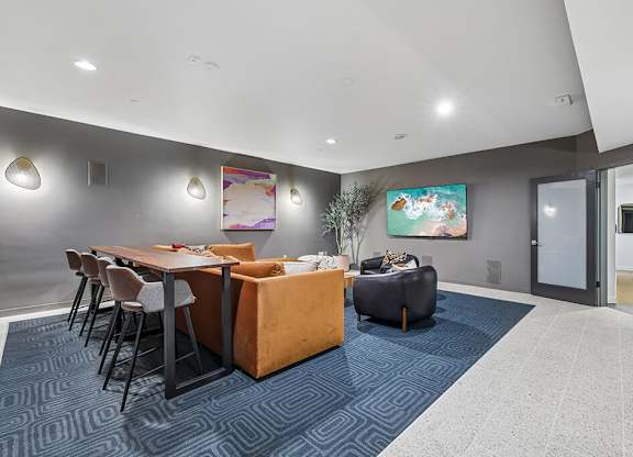 A modern dining area with a blue carpet and a painting on the wall.