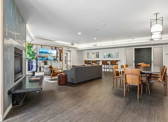 A modern living room with a grey sofa, wooden chairs, and a coffee table.