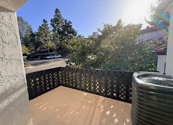 A balcony with a black railing and a wall-mounted air conditioning unit.