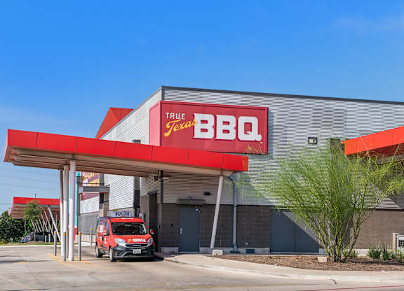 A red and white True BBQ Jax restaurant with a red truck parked in front.