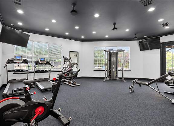 A spacious gym with a variety of exercise equipment including treadmills, stationary bikes, and weight machines.