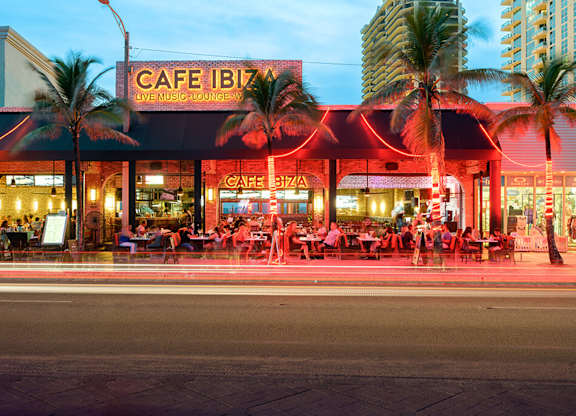 Cafe Ibiza is a live music lounge with palm trees in front.