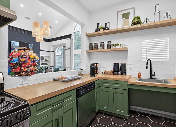 A kitchen with green cabinets and a wooden counter.