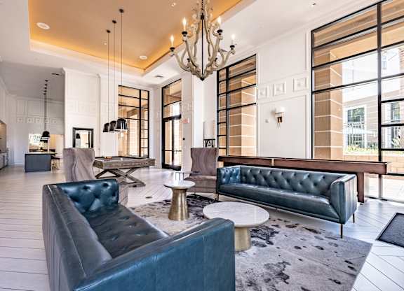 A large room with a blue couch and a chandelier hanging from the ceiling.