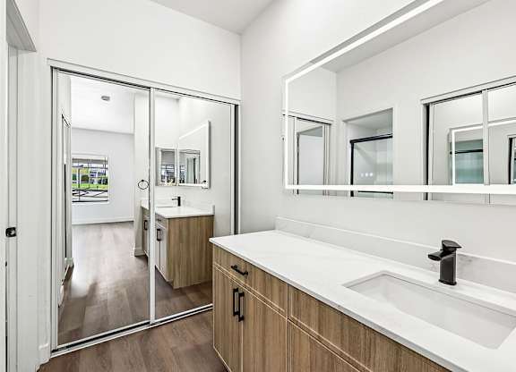 A bathroom with a sink, mirrors and a shower.