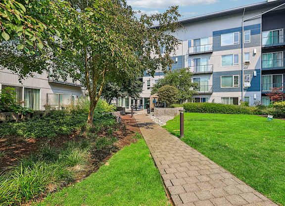 A walkway leads through a grassy area between two apartment buildings.