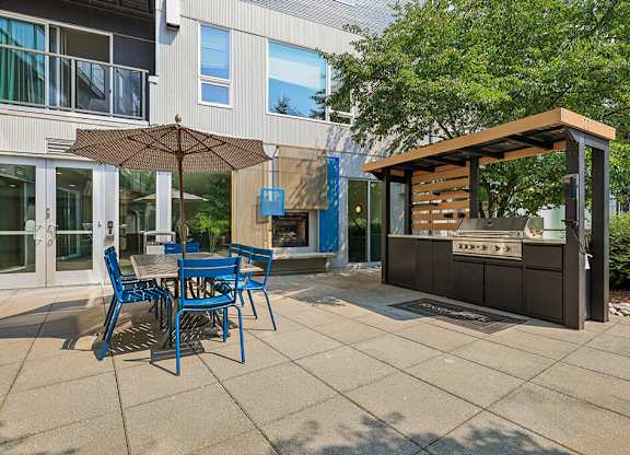 A patio with a table and chairs and a grill.