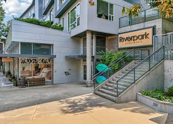 A modern building with the sign "Riverpark Apartments" on the front.