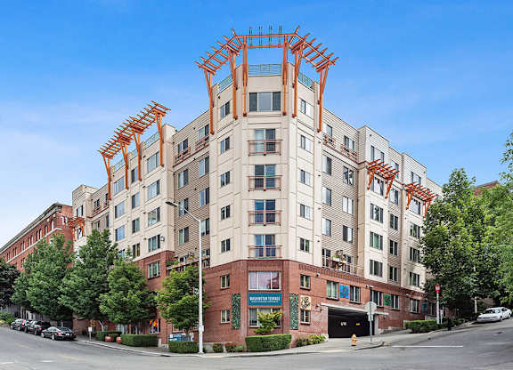 A large building with a red and white facade is under construction with scaffolding on the top floor.