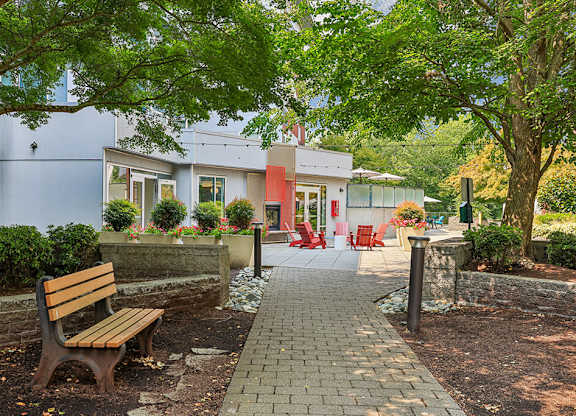 A wooden bench sits in front of a building with a red door.
