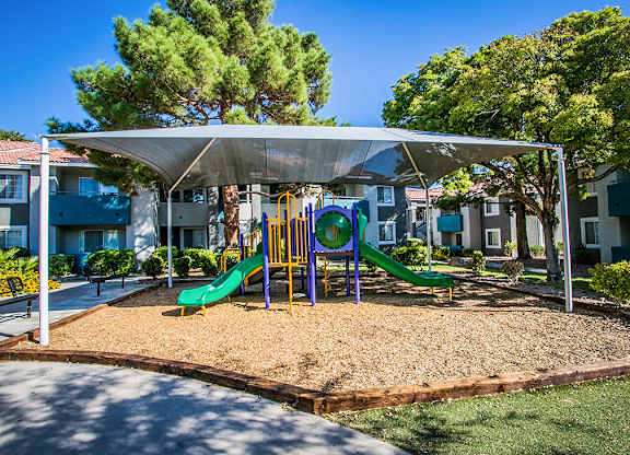 a playground with slides and a swing set in a park