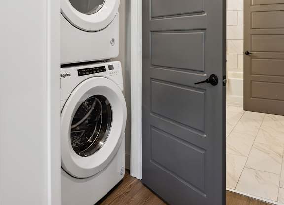 A white dryer is in a small laundry closet.