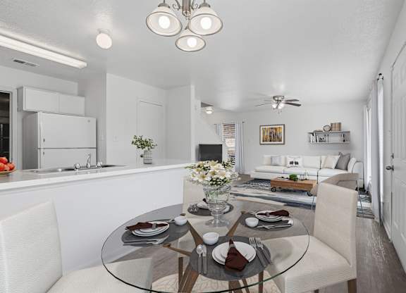 A modern dining room with a glass table and white chairs.