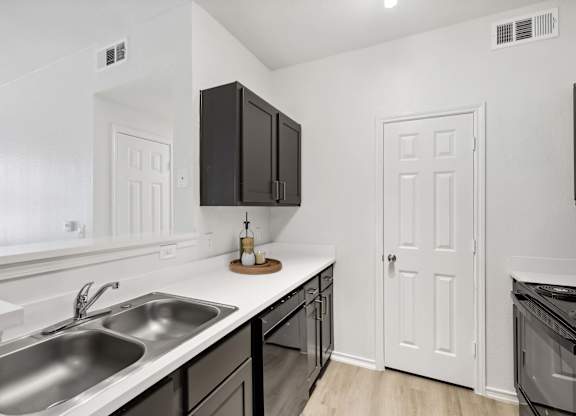 A kitchen with a sink, stove, and cabinets.