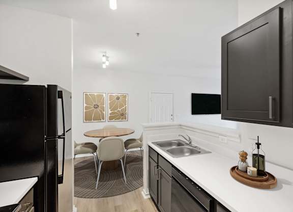 A modern kitchen with a black refrigerator and a white countertop.
