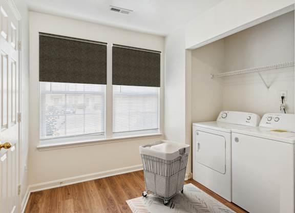 A laundry room with a basket of clothes and a washer and dryer.