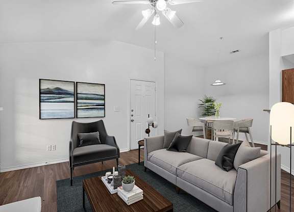 A living room with a grey couch, a black chair, a coffee table, and a painting on the wall.