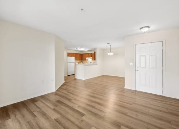 an empty living room and kitchen with a white door