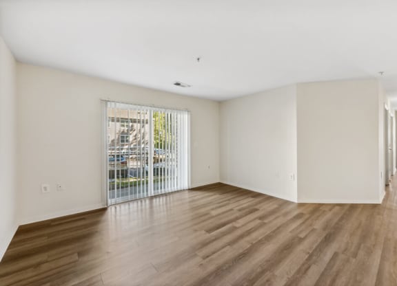 an empty living room with a door to a balcony