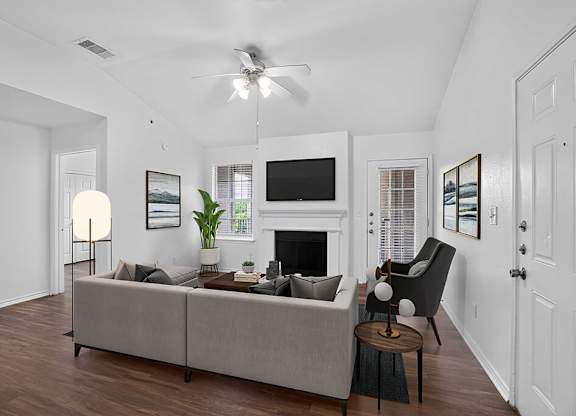 A living room with a grey couch, a fireplace, and a television.