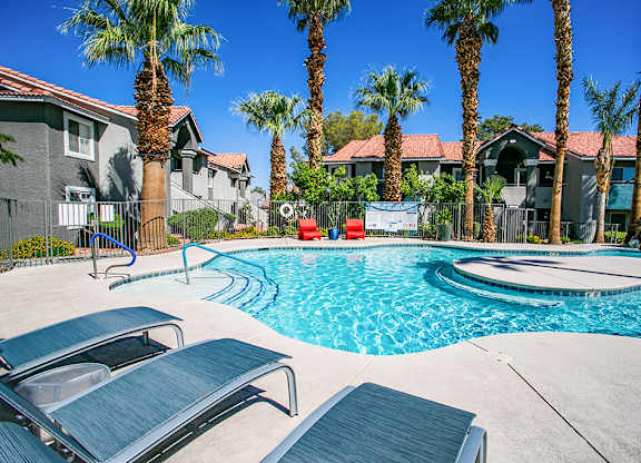 a swimming pool with two chairs and palm trees