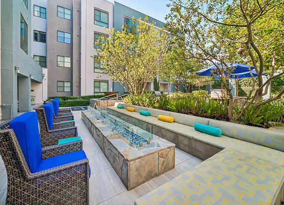 A patio with blue chairs and a table with a glass top.
