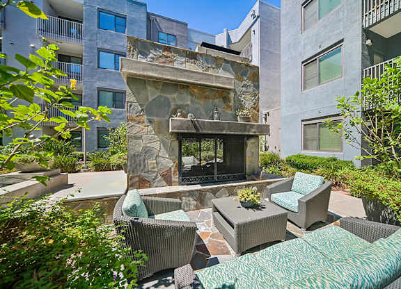 A patio with a fireplace and chairs.