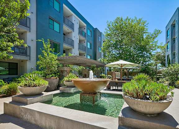 A modern courtyard with a fountain and potted plants.