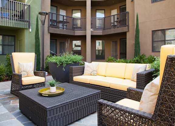 A patio with a sofa, chairs and a table.