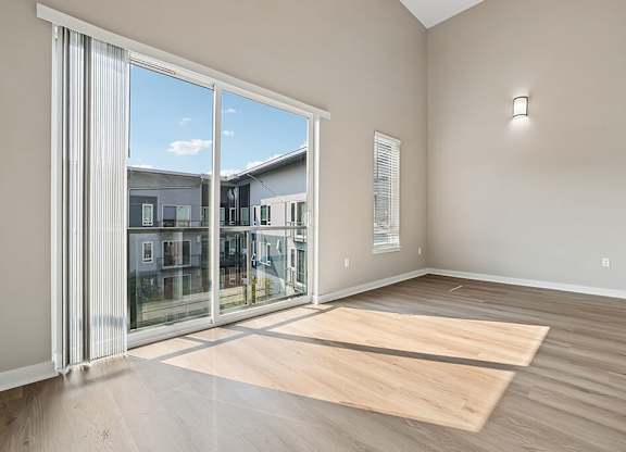 A room with a large sliding glass door and wooden flooring.