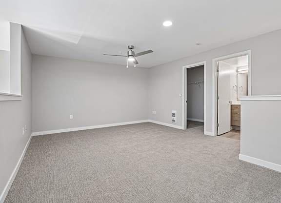 A spacious room with a ceiling fan and carpeted floor.