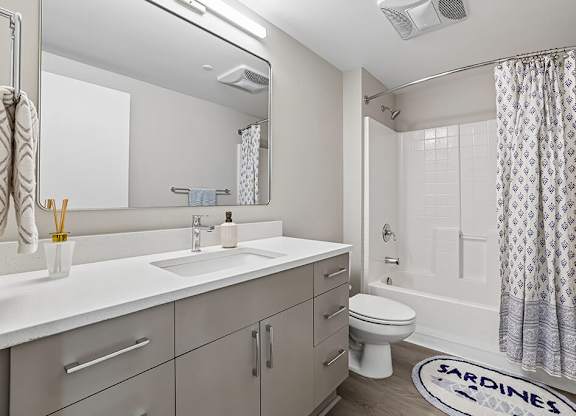 A bathroom with a white sink, toilet, and a shower with a curtain.