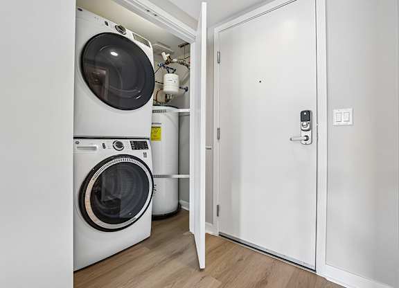 A white door is open to a room with a washing machine and dryer.