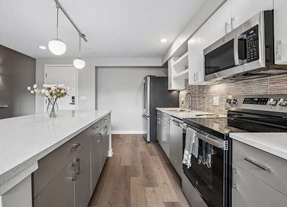 A modern kitchen with stainless steel appliances and wooden floors.