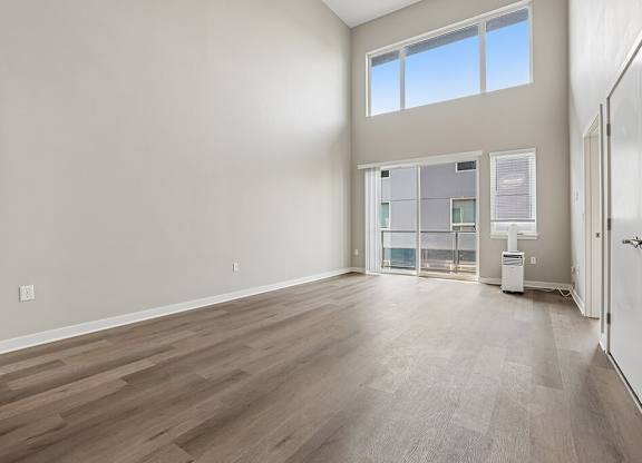 A large empty room with wooden flooring and a window.