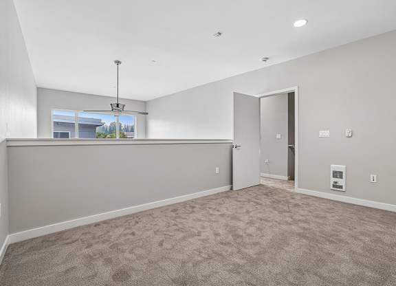 A room with a carpeted floor and a window showing a view of trees and a building outside.