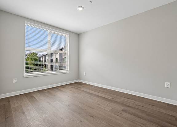 A room with a window and wooden flooring.
