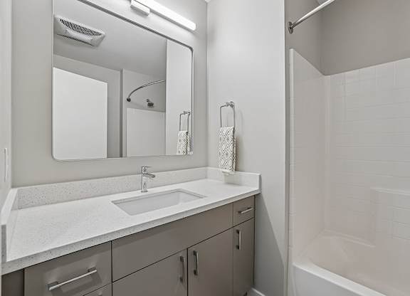 A white bathroom with a sink, mirror, and shower.