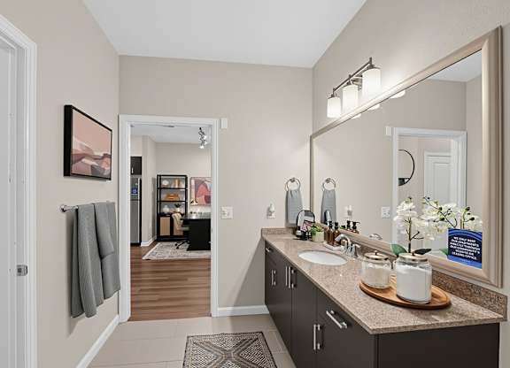 A bathroom with a sink, mirror, and a framed picture on the wall.