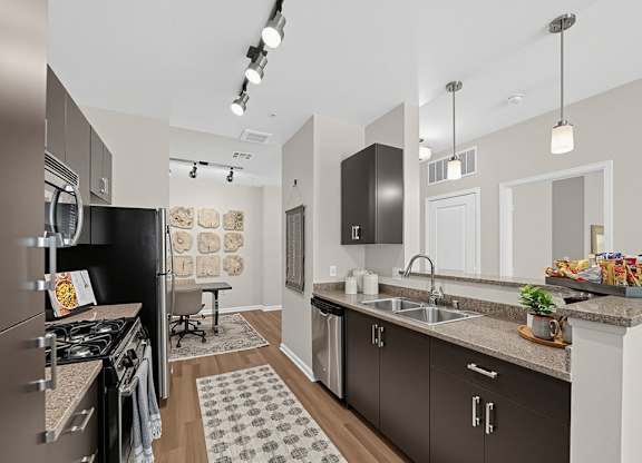 A modern kitchen with dark brown cabinets and a black refrigerator.