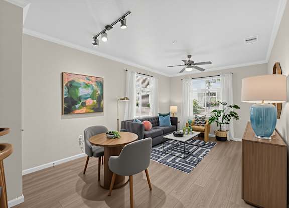 A living room with a grey couch, a round table, and a painting on the wall.