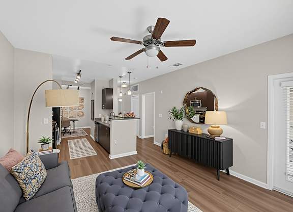 A living room with a grey couch and a round ottoman.