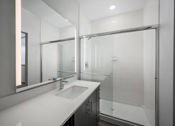 A modern bathroom with a sink, mirror, and shower.