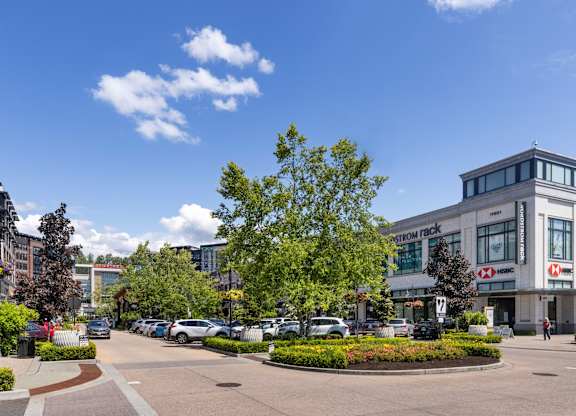 A sunny day at the entrance of a modern building with a parking lot in front.