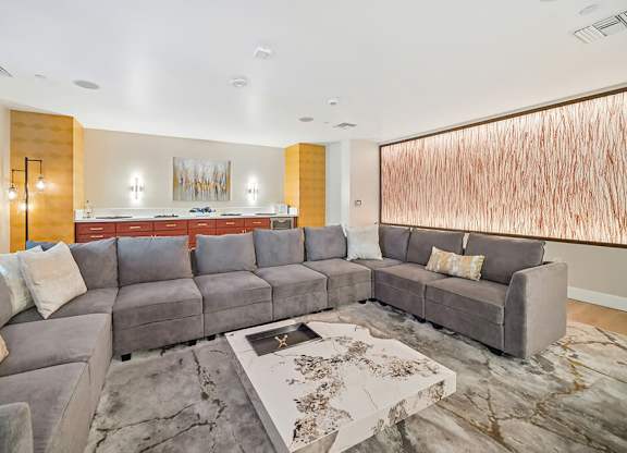 A modern living room with a grey sofa and a large abstract painting on the wall.