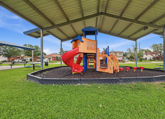 A playground with a red slide and a blue and orange structure.